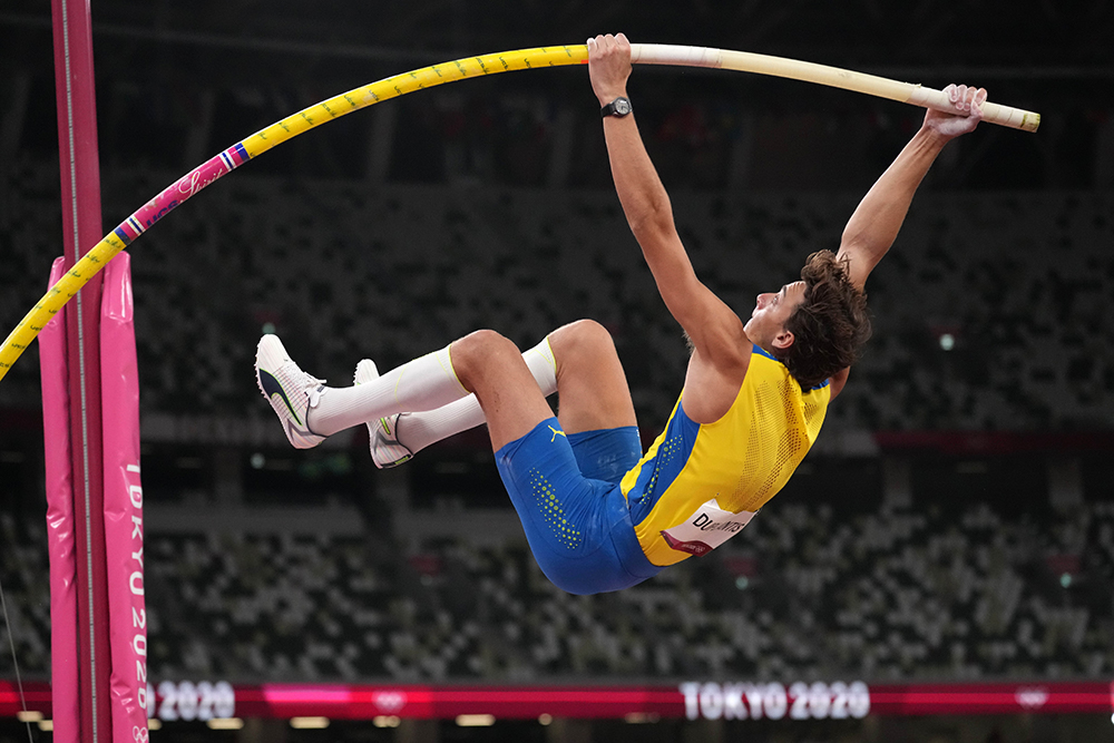 Pole vaulter at the apex of a vault against a Wasatch sunset